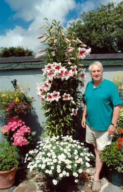 Geraldine's husband, Gerald, standing next to her tree lillies